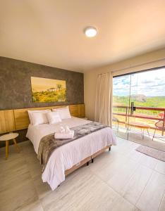 蒙蒂达斯加梅莱拉斯Entre Serras Gastropub e Chalés的一间卧室设有一张床和一个大窗户