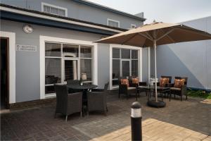 鲸湾港Protea Hotel by Marriott Walvis Bay Indongo的庭院配有桌椅和遮阳伞。