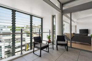 悉尼Urban Rest Double Bay Apartments的阳台配有椅子、沙发和窗户。