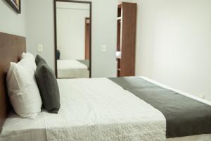 巴西利亚Roma Hotel by H Hotéis - Airport的一间卧室配有带枕头和镜子的床