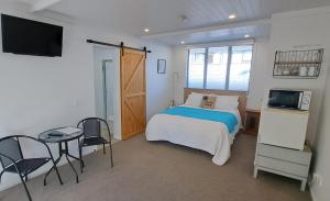 怀蒂昂格Guest Nest in Whitianga - 2 min walk to Beach的一间卧室配有一张床、一张桌子和一台电视。