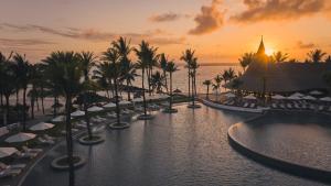 贝尔马尔LUX* Belle Mare Resort & Villas的棕榈树和日落的游泳池