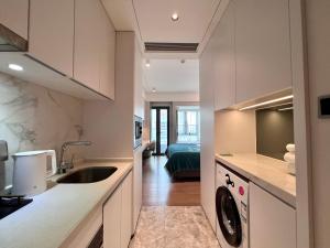 深圳凯森希悦酒店公寓(深圳国际会展中心店)的厨房配有水槽、洗衣机和烘干机