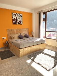 卡索尔Himtrek Stays, Kasol的一间卧室配有一张带橙色墙壁和窗户的床