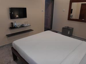 MaemDE RUSH FARM的卧室配有白色的床和平面电视。