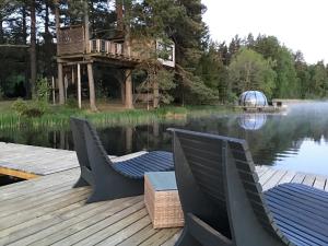 DuķuriTreehouse Čiekurs的一个带两把椅子的甲板和水边的树屋