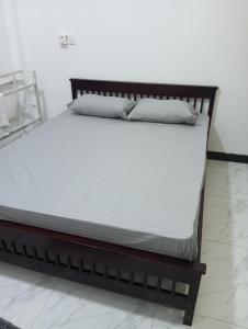 加姆珀哈Anne's Homestay的一张带白色床单和枕头的床