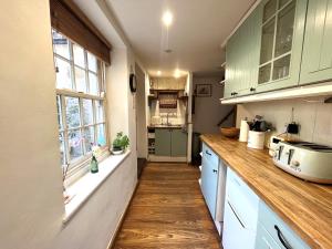 埃文河畔布拉德福Bath Road Holiday的铺有木地板的厨房配有绿色橱柜