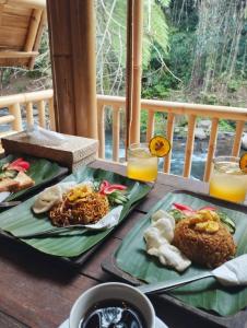 TampaksiringAksha Riverside Ubud的桌上的两盘食物和橙汁
