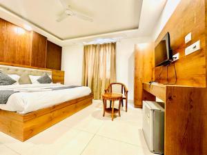 新德里Hotel The Glory Near Delhi International Airport的一间卧室配有一张床和一台电视