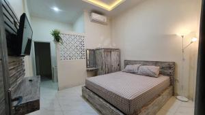 NegaraAna homestay的一间卧室配有一张床,并在一间客房内配有电视。
