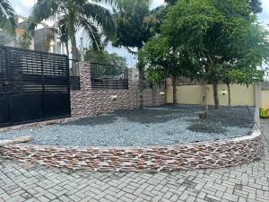 阿克拉Coolzzy GM247 Homes-Accra Kwabenya Villas的建筑物前有树的栅栏
