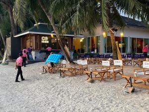 象岛Coconut Beach Resort, Koh Chang的一个人在沙滩上散步,那里有桌椅