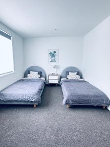 奥克兰Stylish Industrial Holiday House in Pakuranga Free Wifi Netflix的一间卧室配有两张床和一张桌子