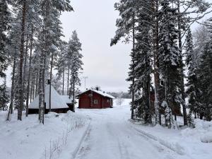SonkaKenttäniemi Cottages的红谷仓旁一条有雪覆盖的道路