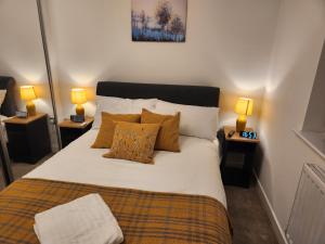 曼彻斯特Beautifully Fab 3 bedroom 4 beds New home 8 guests Stretford Trafford的一间卧室配有一张带枕头的床和两盏灯。