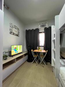 马尼拉Iza's Condo in Filinvest Alabang的客房设有桌子、电视和床。