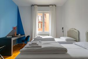 博洛尼亚Everyday Apartments Corte Petroni的一间卧室设有三张床、一张桌子和一个窗户。