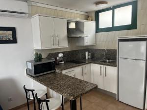 马斯帕洛马斯Playa Ingles central cozy apartment的厨房配有白色橱柜和带微波炉的台面。