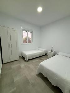 加的斯Mirador el atardecer的白色的客房设有两张床和窗户。