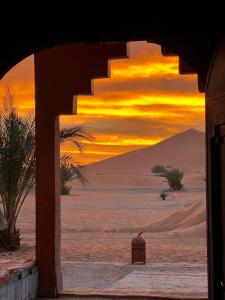 梅尔祖卡Hotel Camping Les Roses Des Dunes的透过一条门廊看到沙漠中的日落