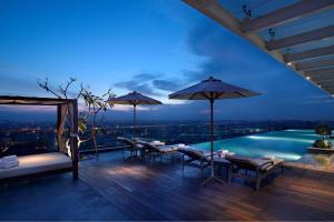 棉兰棉兰JW万豪酒店的一个带桌子和遮阳伞的庭院和一个游泳池