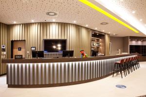 哈尔伯格摩斯Hampton by Hilton Munich Airport South的大堂设有带椅子和电视的酒吧