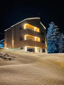 珀尔蒂尼什NORDIC Apartamente Păltiniș的一座晚上下雪的建筑
