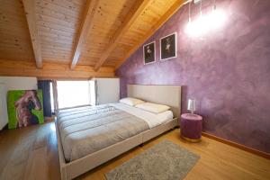 科马诺泰梅LE MUSE Comano Terme Holiday 2, primo piano的一间卧室配有一张床和紫色的墙壁