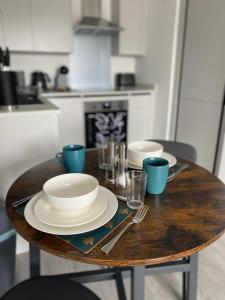 赫默尔亨普斯特德Hemel Apartments- Tranquil Haven的一张木桌,上面有盘子和盘子