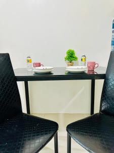 马尼拉Sea Residences by Jan & Val Alano的一张桌子,上面有两把椅子和盘子,上面有植物