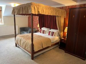 斯卡伯勒East Ayton Lodge Hotel, Scarborough的一间卧室配有一张天蓬床和一把椅子