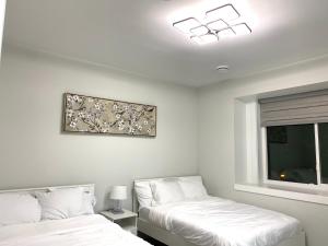 温哥华Modern and Brand new house near PNE的一间卧室设有两张床,窗户墙上挂着一幅画。