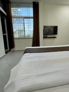 乌贾因Tekri Farms and Retreat的卧室设有一张白色大床和一扇窗户。