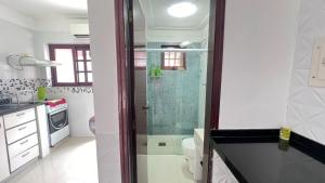 乌巴图巴Condominio Village Americana的一个带玻璃淋浴间的浴室,位于后门