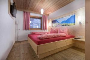 耶岑斯Bergsonnhof的一间卧室配有一张带红色枕头的大型木制床。