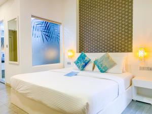 马富施Velana Beach Hotel Maldives的白色卧室配有白色大床和蓝色枕头