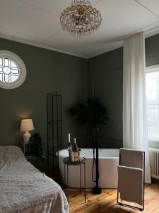 NorbergPastors Prästgården的一间卧室配有一张床、一个浴缸和一个吊灯。