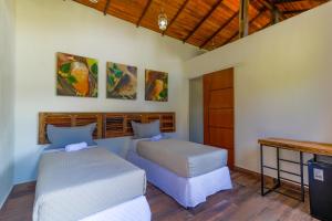 特雷索波利斯Art Green Teresópolis的一间卧室配有两张床、一张桌子和一张书桌
