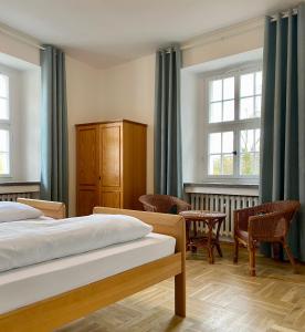 Kavaliershaus neben Schloss Rauenstein的一间卧室设有两张床、椅子和窗户。
