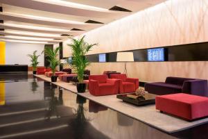 Ferno喜来登米兰马尔彭萨机场酒店及会议中心的大堂设有红色和紫色椅子和植物