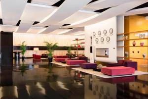 Ferno喜来登米兰马尔彭萨机场酒店及会议中心的大堂设有红色和紫色的椅子和桌子