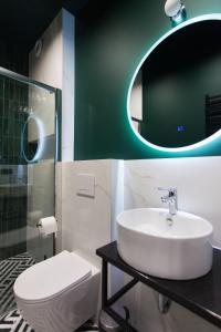 罗兹Apartamenty BIBLIO的一间带水槽、卫生间和镜子的浴室
