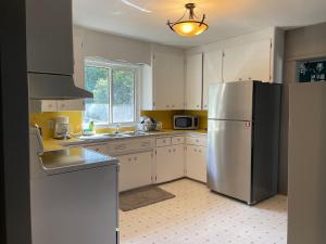 萨斯卡通TheSunshine: Bright&Peaceful 2 Bdrm Character Home的厨房配有不锈钢冰箱和白色橱柜