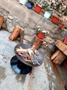 塔尔马Casa de Campo-Hospedaje Munay Wasi的火坑,有木柴,桌子和长凳