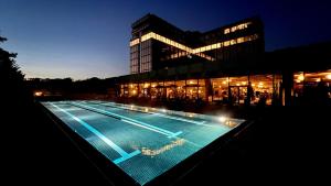 布鲁塞尔Mix Brussels --Gym & Wellness for adults only--的一座游泳池,在晚上在建筑物前