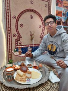 马拉喀什Riad Hostel JAD ZIAD的坐在一盘食物前的人