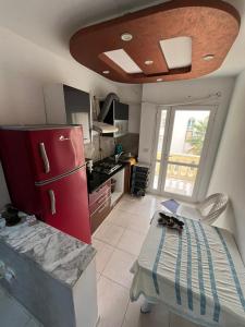 苏塞Appart S plus 2 à Sousse zone touristique的一间带红色冰箱和桌子的小厨房