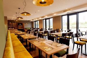 埃滕海姆DiMas Hotel Ettenheim - Rust的餐厅设有木桌、椅子和窗户。