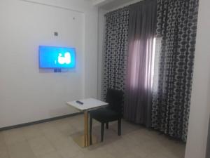 DschangJAD HOTEL Dschang的配有桌子、椅子和电视的房间